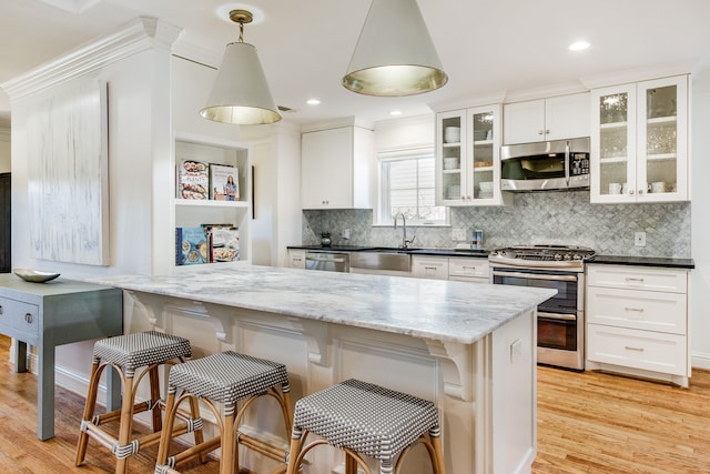 kitchen with a sink, a breakfast bar area, light wood-style floors, and stainless steel appliances