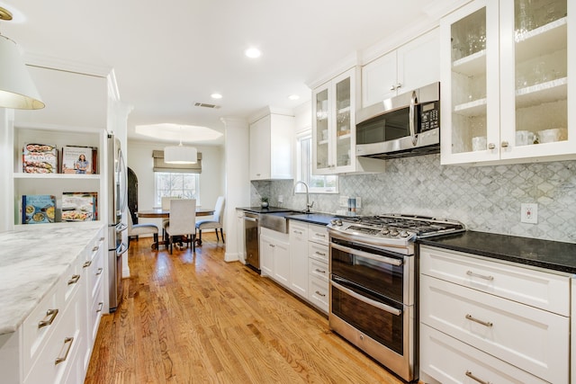 kitchen with light wood-type flooring, visible vents, appliances with stainless steel finishes, white cabinets, and decorative backsplash