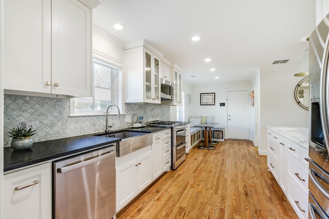 kitchen with visible vents, a sink, decorative backsplash, appliances with stainless steel finishes, and crown molding