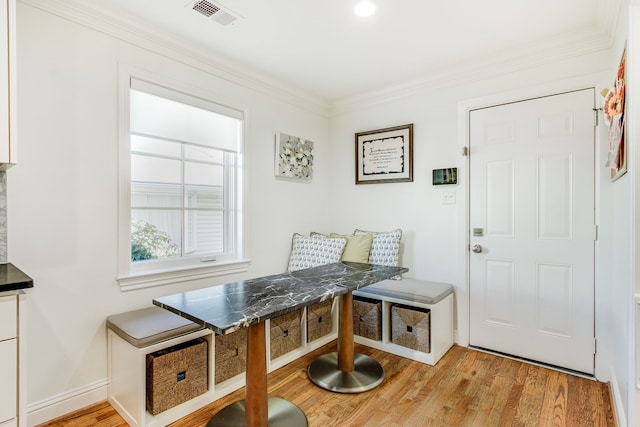 interior space with light wood finished floors, visible vents, baseboards, and ornamental molding