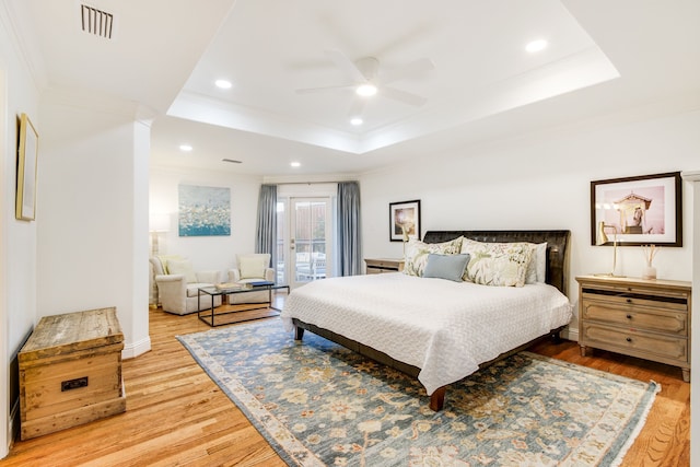 bedroom with a raised ceiling, wood finished floors, ornamental molding, and access to exterior