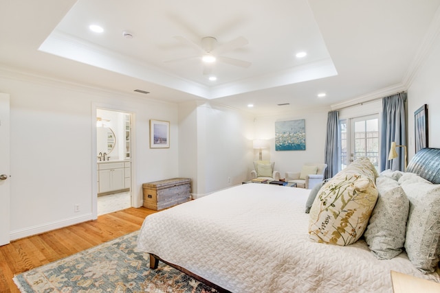 bedroom with a tray ceiling, wood finished floors, baseboards, and ornamental molding