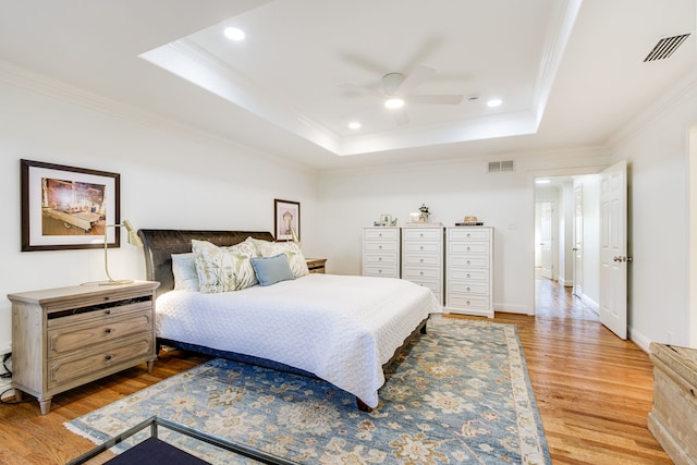 bedroom featuring visible vents, a raised ceiling, light wood-style floors, and ornamental molding