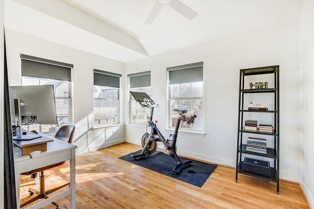 exercise room with baseboards, light wood-style floors, ceiling fan, and vaulted ceiling