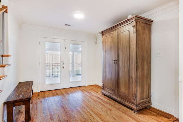 doorway with visible vents, baseboards, light wood-style flooring, french doors, and crown molding