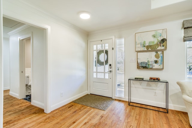 foyer with crown molding, baseboards, and light wood finished floors