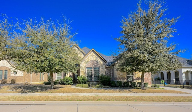 view of front of house with brick siding, stone siding, and fence