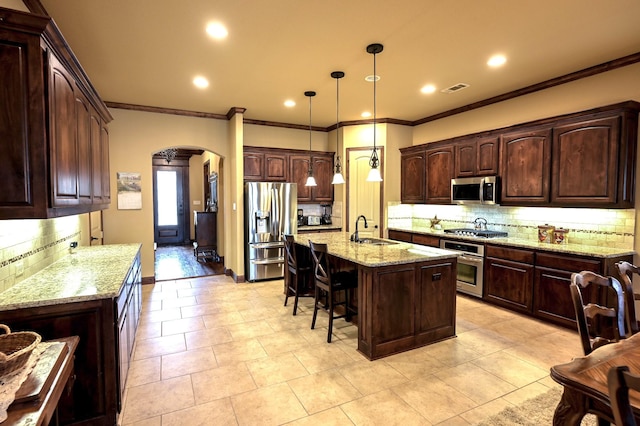 kitchen with a breakfast bar area, light stone counters, arched walkways, a sink, and stainless steel appliances