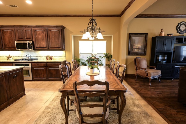 dining room featuring light tile patterned floors, visible vents, an inviting chandelier, and crown molding