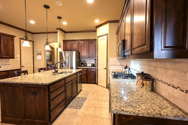 kitchen with a sink, stainless steel appliances, dark brown cabinets, and a center island with sink