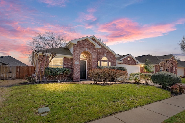 view of front facade with a garage, brick siding, a front lawn, and fence