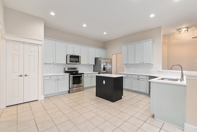 kitchen with a center island, light countertops, appliances with stainless steel finishes, a peninsula, and a sink