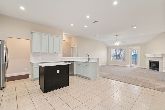 kitchen with visible vents, a kitchen island, a peninsula, appliances with stainless steel finishes, and open floor plan