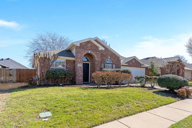 view of front of property featuring a front yard, an attached garage, fence, and brick siding