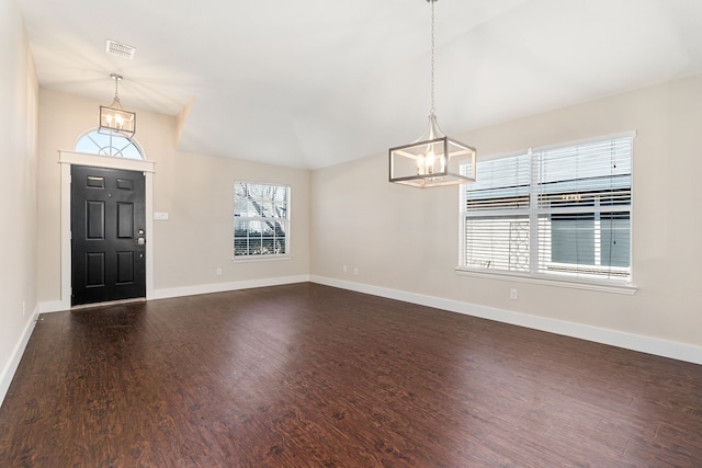 foyer entrance featuring a chandelier, dark wood finished floors, and baseboards