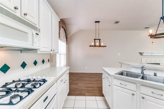 kitchen with white appliances, light countertops, and a sink