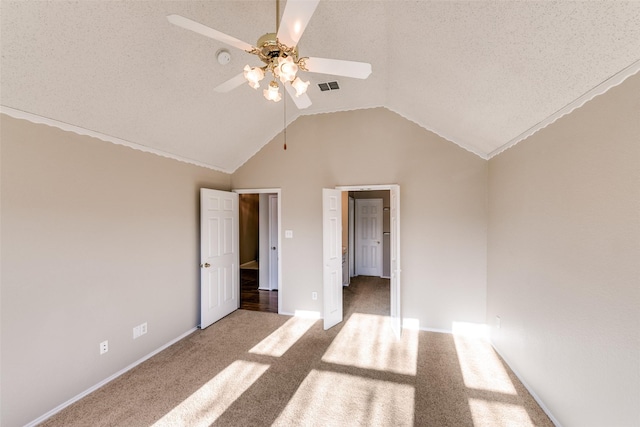 unfurnished bedroom with visible vents, a textured ceiling, carpet, and vaulted ceiling