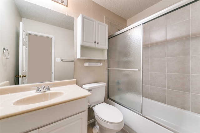 bathroom with vanity, shower / bath combination with glass door, a textured ceiling, toilet, and a textured wall