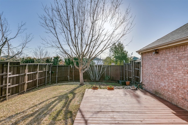 wooden terrace featuring a lawn and a fenced backyard