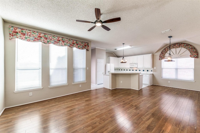 unfurnished living room featuring visible vents, ceiling fan, vaulted ceiling, hardwood / wood-style flooring, and a textured ceiling