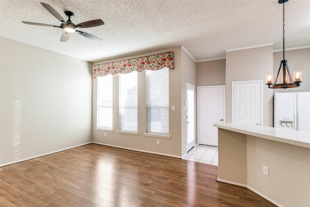 unfurnished living room with ceiling fan with notable chandelier, a textured ceiling, and wood finished floors