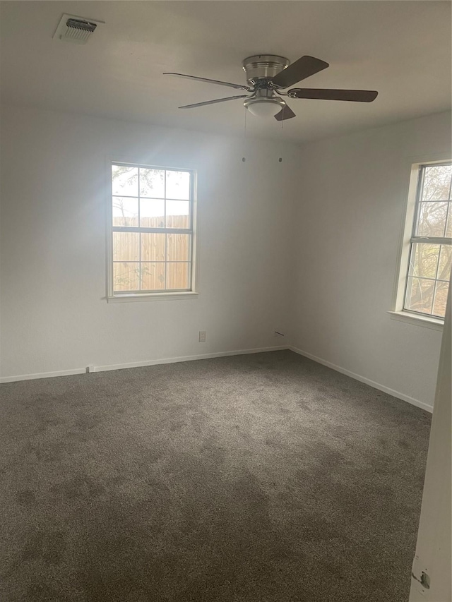 spare room with visible vents, dark carpet, baseboards, and a ceiling fan