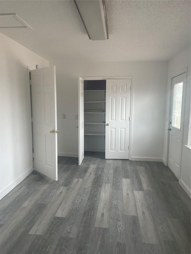 unfurnished bedroom featuring baseboards, a textured ceiling, and wood finished floors