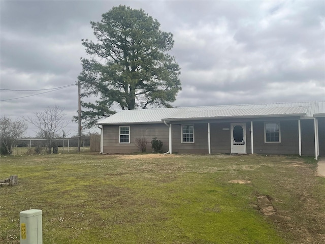 view of front of house featuring metal roof, a front lawn, and fence