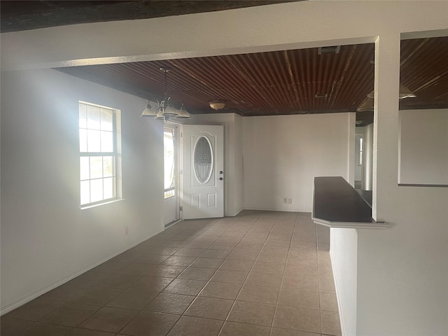 interior space featuring dark tile patterned floors, wood ceiling, and a chandelier