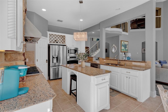 kitchen featuring ventilation hood, light stone counters, light tile patterned floors, appliances with stainless steel finishes, and a sink