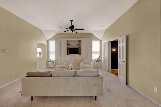 living room featuring a wealth of natural light, visible vents, arched walkways, and light colored carpet