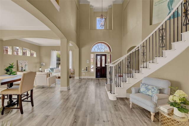 foyer entrance with baseboards, wood finished floors, ornamental molding, and stairs