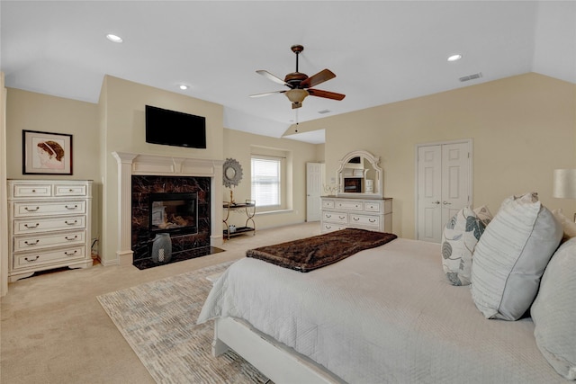 bedroom featuring visible vents, a premium fireplace, recessed lighting, vaulted ceiling, and light colored carpet