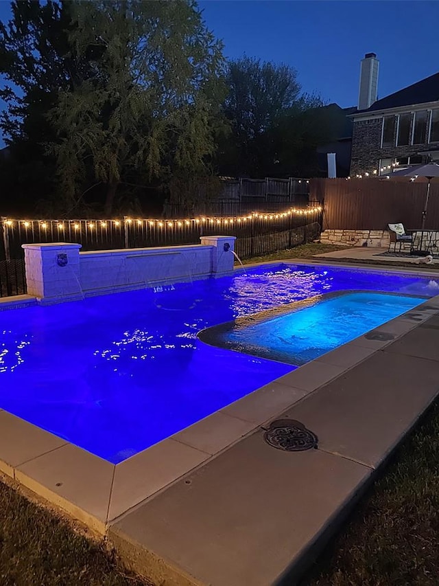 pool at twilight with a patio, a fenced backyard, and a fenced in pool