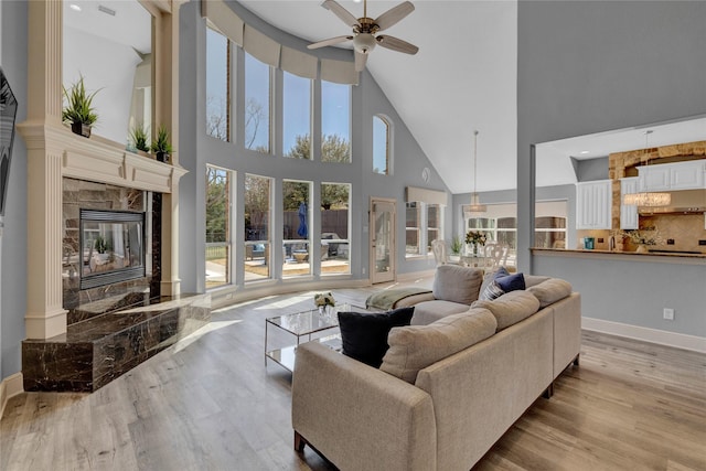 living area with baseboards, a ceiling fan, wood finished floors, and a fireplace