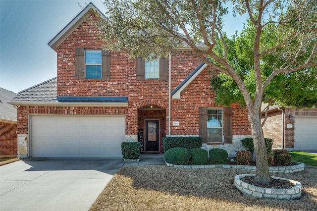 traditional-style home with brick siding, concrete driveway, roof with shingles, a garage, and stone siding