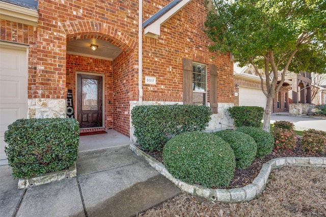 property entrance featuring brick siding, an attached garage, and concrete driveway