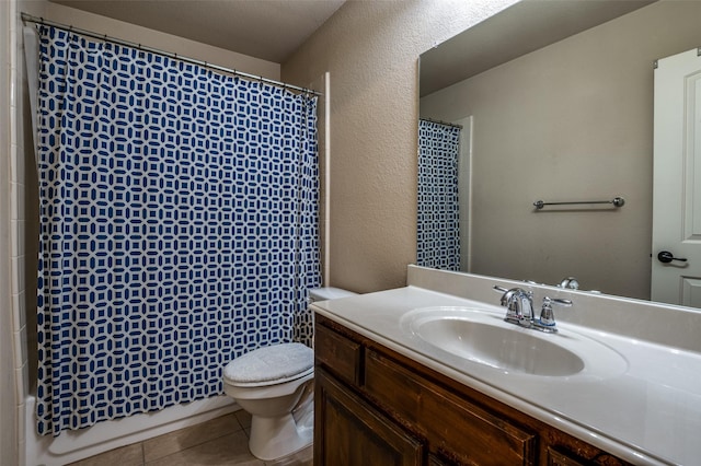 bathroom with tile patterned flooring, toilet, vanity, and a textured wall