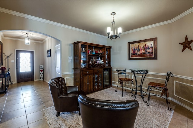 living area with tile patterned floors, arched walkways, an inviting chandelier, and crown molding