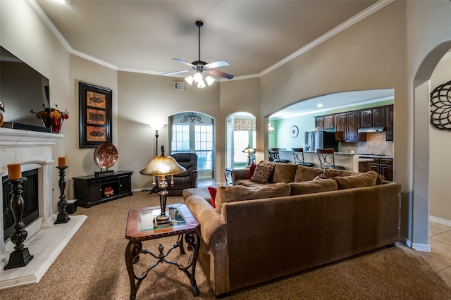 living room featuring a tiled fireplace, crown molding, and baseboards