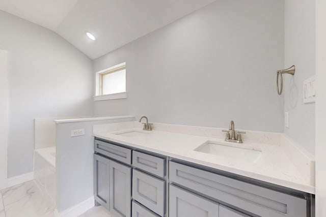 full bath featuring a sink, lofted ceiling, a bathtub, and marble finish floor