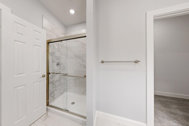 bathroom featuring baseboards, marble finish floor, and a marble finish shower