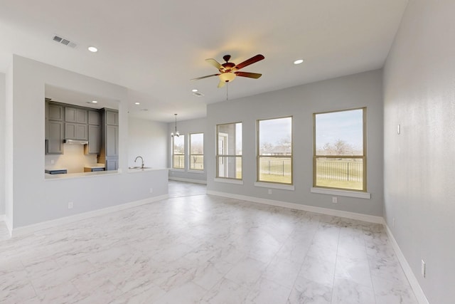 unfurnished living room featuring baseboards, visible vents, recessed lighting, a sink, and ceiling fan with notable chandelier