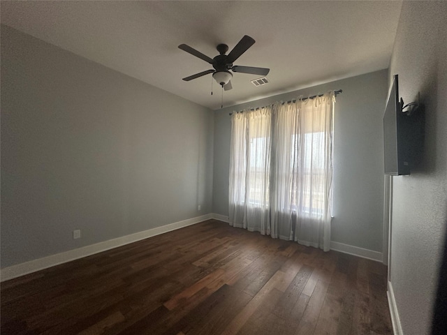 empty room with ceiling fan, visible vents, baseboards, and dark wood-style floors