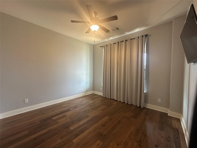 empty room with visible vents, baseboards, dark wood finished floors, and a ceiling fan