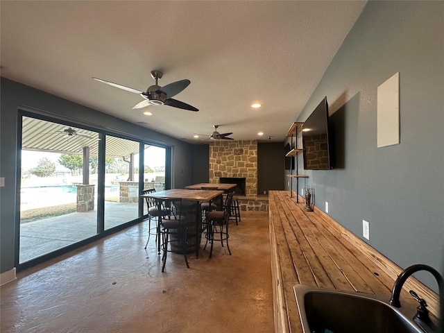 dining space featuring concrete flooring, recessed lighting, a fireplace, a textured ceiling, and a ceiling fan