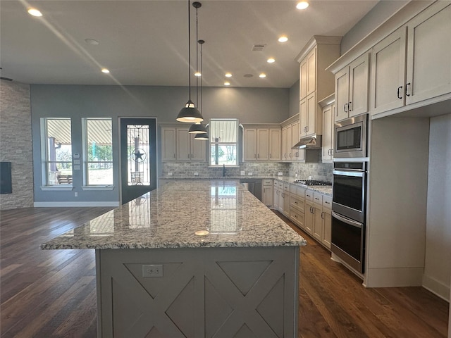 kitchen featuring visible vents, stainless steel appliances, under cabinet range hood, backsplash, and a center island