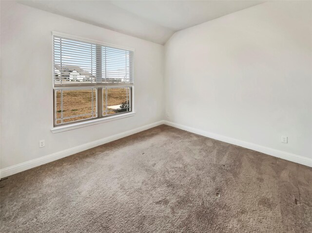 carpeted spare room with baseboards and lofted ceiling