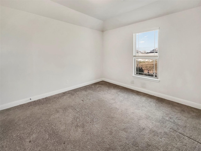 unfurnished room with carpet flooring, baseboards, and vaulted ceiling