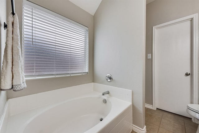 full bathroom with tile patterned flooring, a garden tub, toilet, and vaulted ceiling